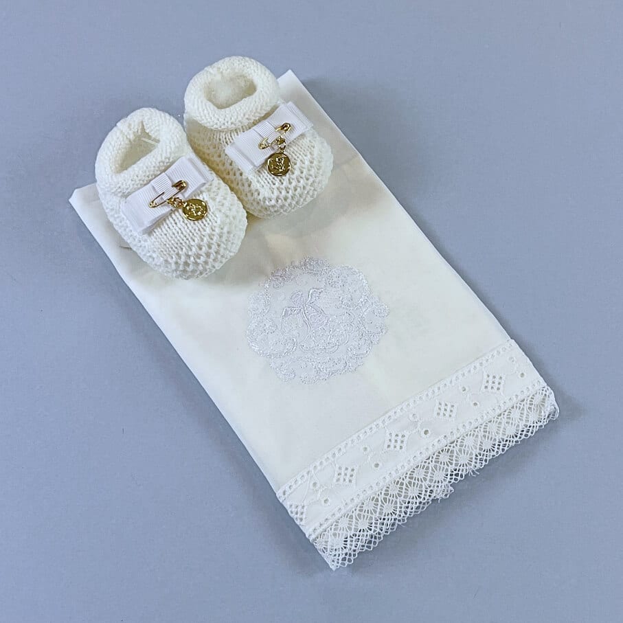 Sapatinho branco de batizado junto com toalha de batizado.